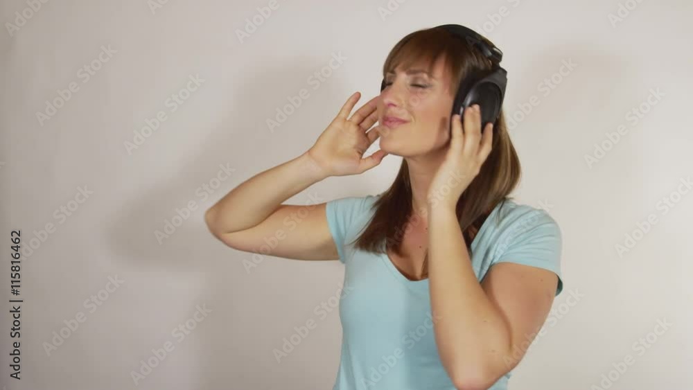SLOW MOTION: Cheerful brunette dancing to funky music from headphones SLOW MOTION: Cheerful brunette dancing to funky music from headphones
