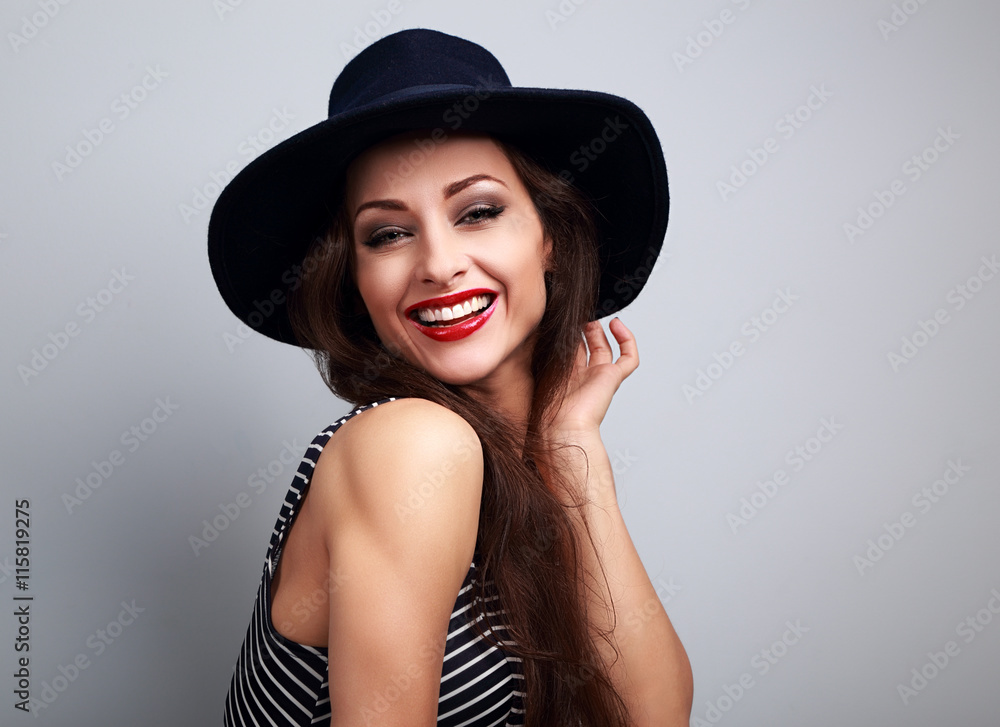 Happy laughing young woman in black hat looking on blue backgrou Happy laughing young woman in black hat looking on blue backgrou