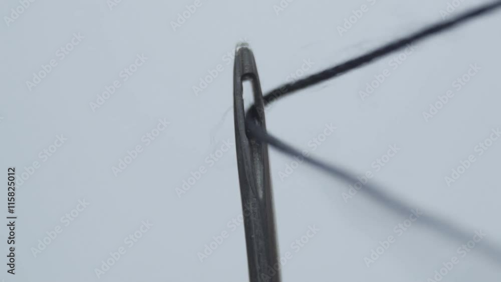 Threading black thread through the eye of a needle. Macro Threading black thread through the eye of a needle. Macro