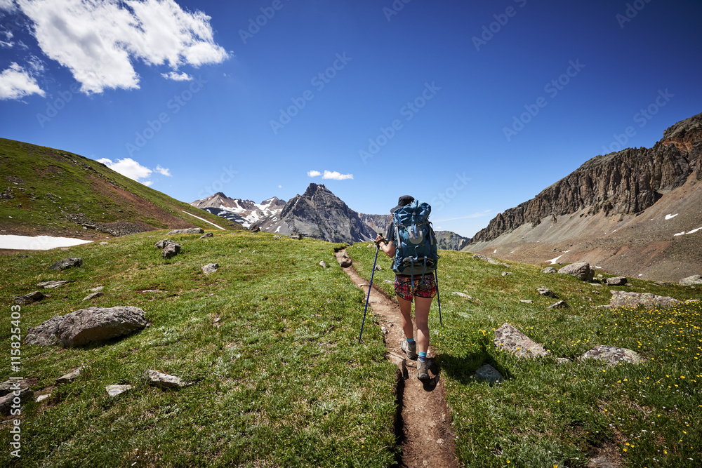 Obraz premium a young woman hiking with a backpack in the mountains