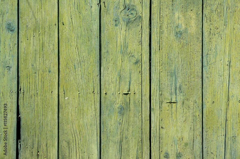 Old weathered green yellow grunge boards surface of wooden garden fence as background