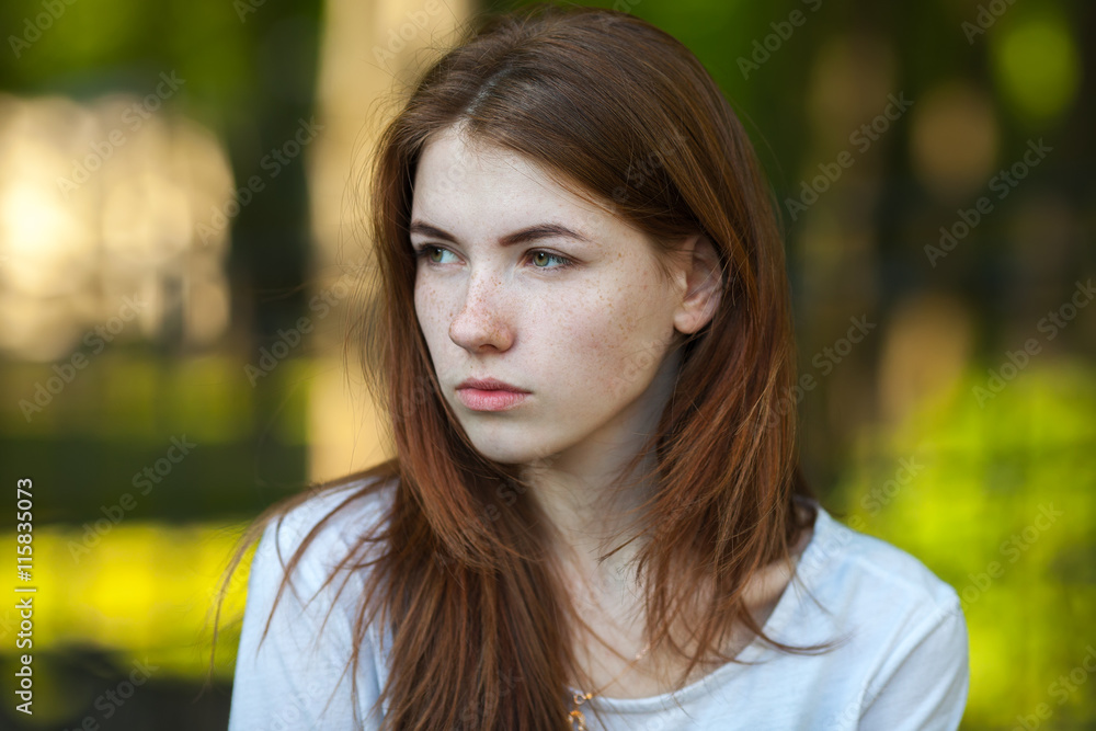 Portrait of a serious young redhead woman outdoor blurry forest park background Portrait of a serious young redhead woman outdoor blurry forest park background