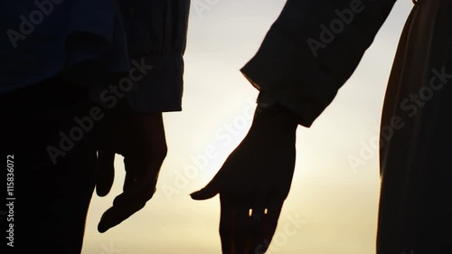 4K Silhouette hands of a couple come together at sunset photo