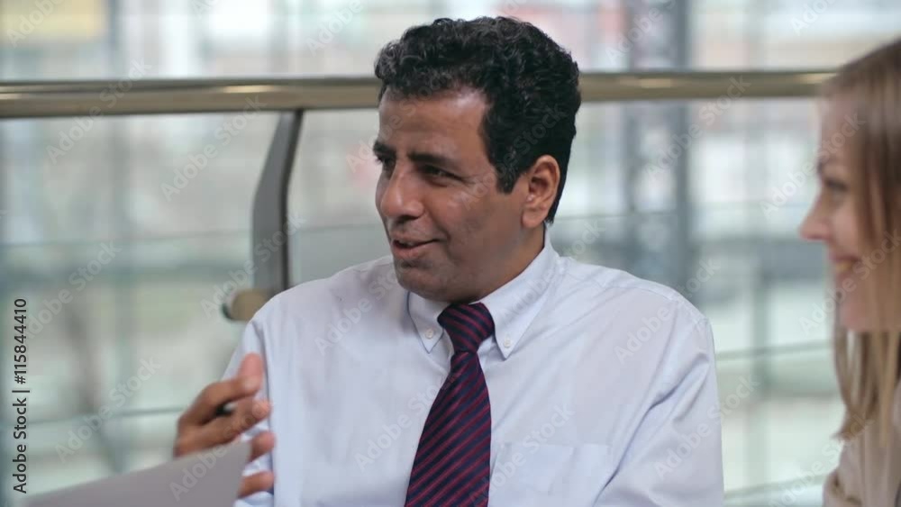 Mid-adult entrepreneur talking to his employees and smiling Mid-adult entrepreneur talking to his employees and smiling