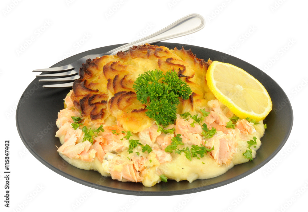 Portion of crispy potato topped fish pie on a black plate Portion of crispy potato topped fish pie on a black plate