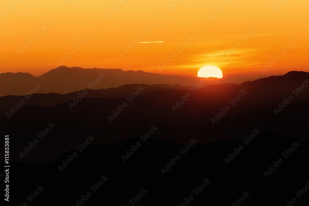 Brilliant and colorful orange sunset with silhouette of mountain range