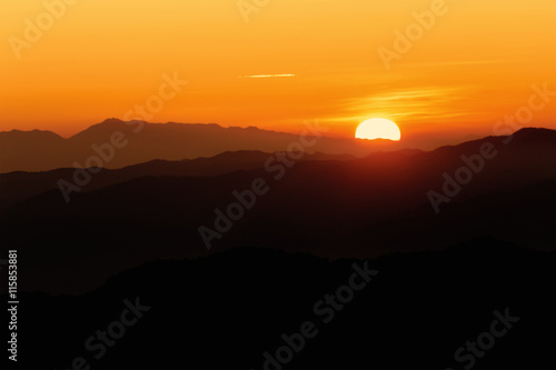 Brilliant and colorful orange sunset with silhouette of mountain range