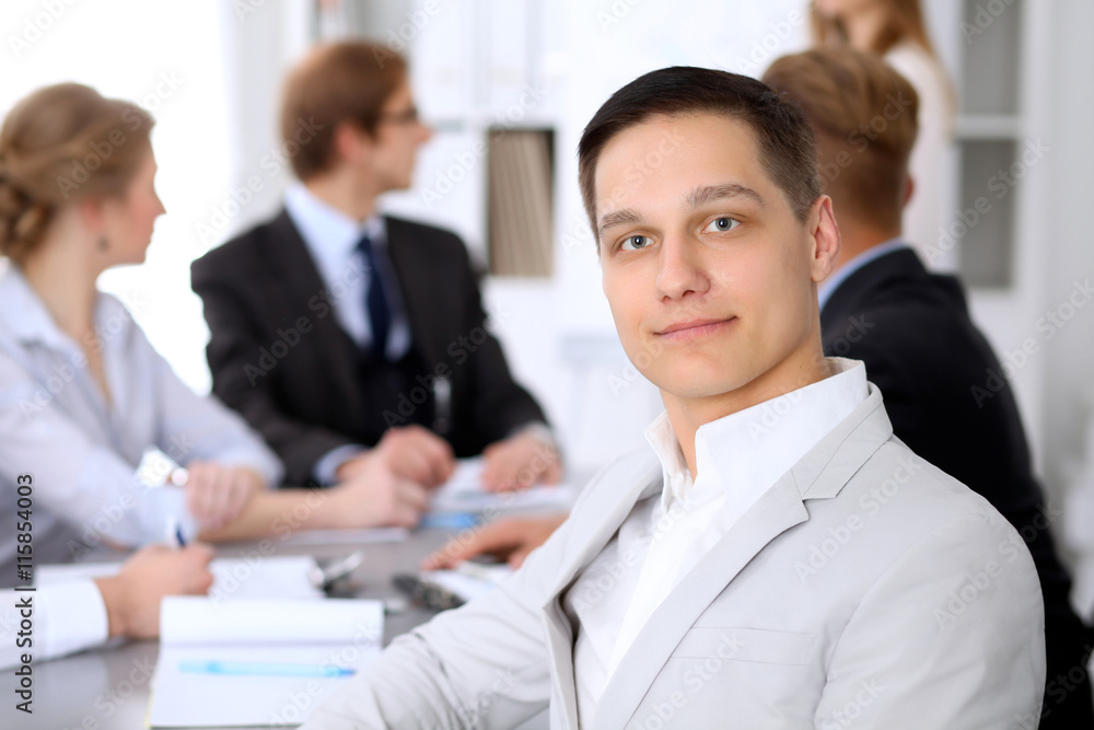 Portrait of business man against a group of business people at a meeting. Portrait of business man against a group of business people at a meeting.