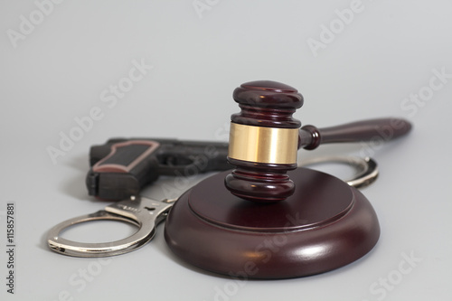 judge's gavel, handgun and handcuffs isolated on gray background