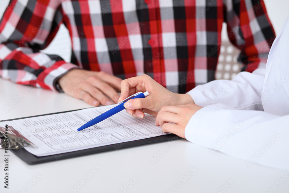 Close-up of a female doctor holding application form while consulting patient Close-up of a female doctor holding application form while consulting patient