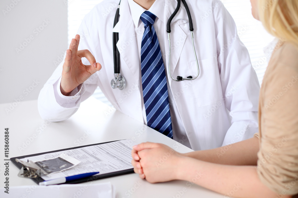 Close-up of a doctor man hands showing ok sign while consulting patient Close-up of a doctor man hands showing ok sign while consulting patient
