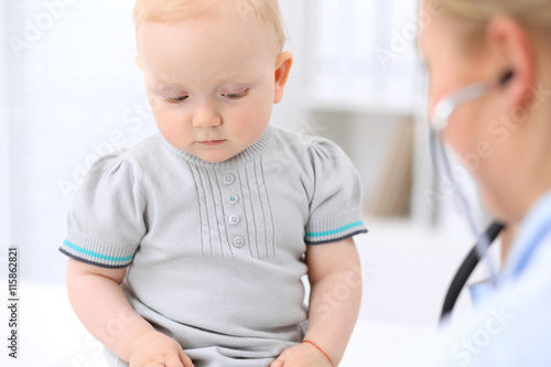 Pediatrician is taking care of baby in hospital. Little girl is being examine by doctor with stethoscope. Health care, insurance and help concept.