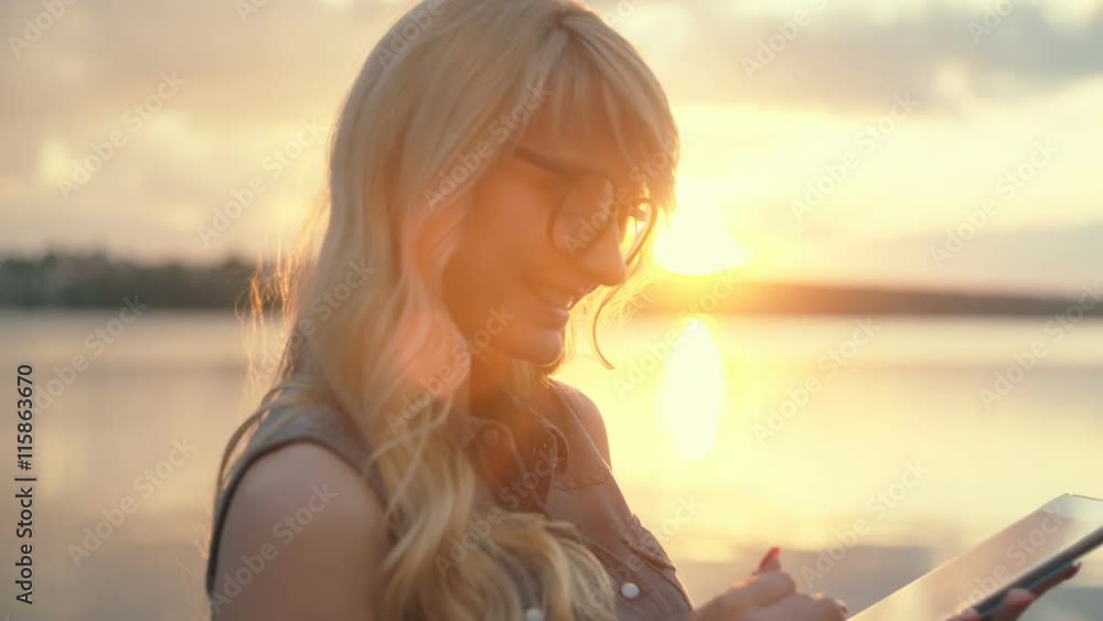 Close-up shot ofwoman working with tablet computer on sunset and sea background. RAW video record. Close-up shot ofwoman working with tablet computer on sunset and sea background. RAW video record.