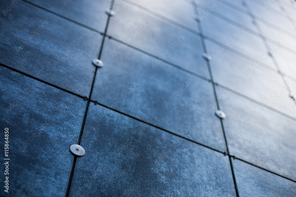 Blurry background of a blue metal plated house facade with light reflections