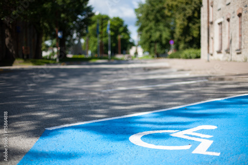 Closeup of an empty handicapped reserved parking space painted blue with a white wheelchair symbol on black asphalt in the city