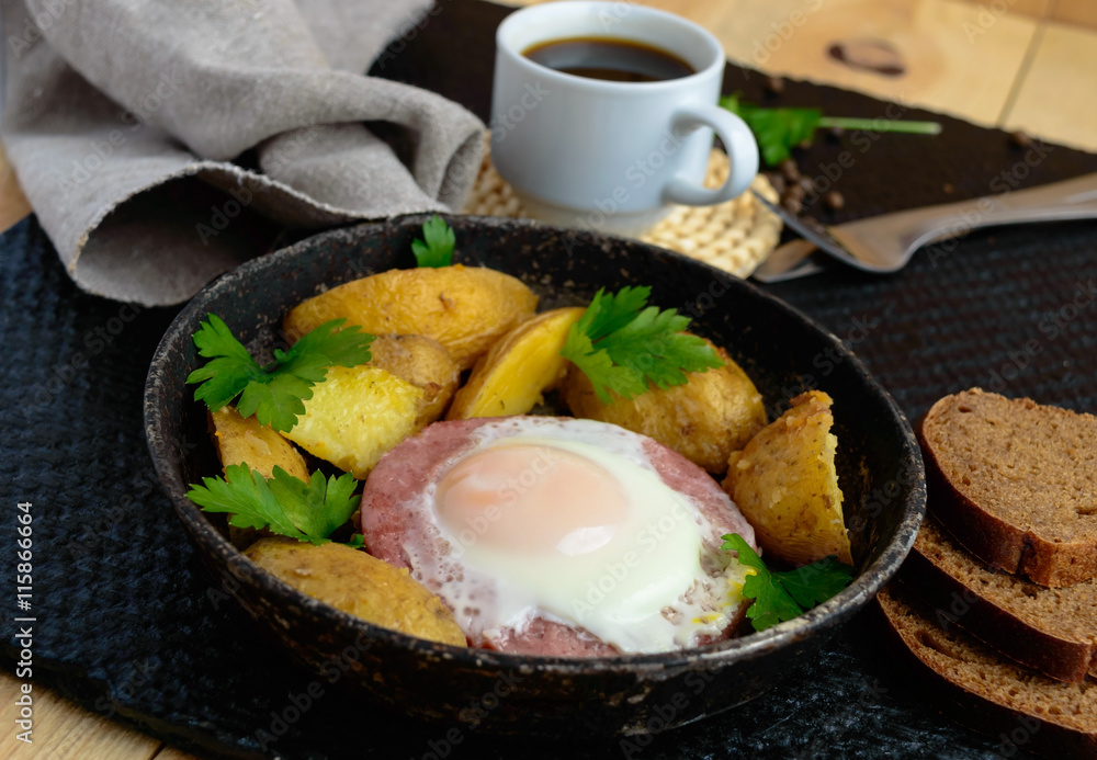 Fried egg in salami and baked potatoes. Submission of a frying pan with a cup of coffee and rye bread. Breakfast. Fried egg in salami and baked potatoes. Submission of a frying pan with a cup of coffee and rye bread. Breakfast.