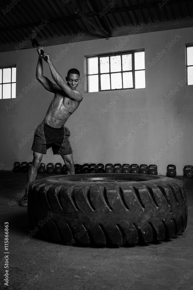 male fitness model hitting a tractor tyre with hammer in a gym during  intense training Stock Photo | Adobe Stock