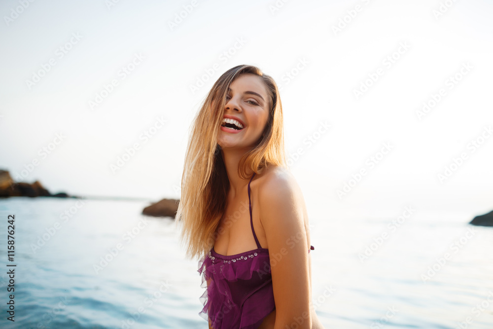 Beautiful young cheerful girl rests at morning beach