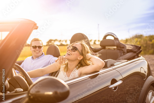 Mit dem Cabrio unterwegs - Verliebtes Paar im Cabrio lacht und ist glücklich  photo