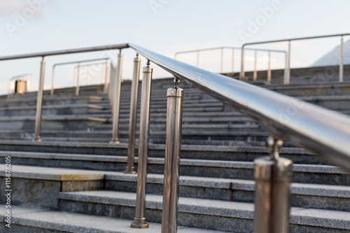 Public metal chrome handrail on gray staircase at city