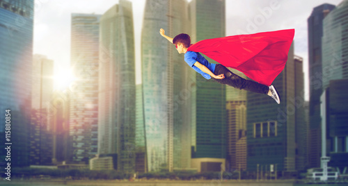 boy in superhero cape and mask flying over city