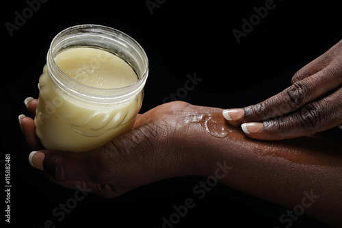 femme noire africaine mettant beurre de karité sur sa peau photo