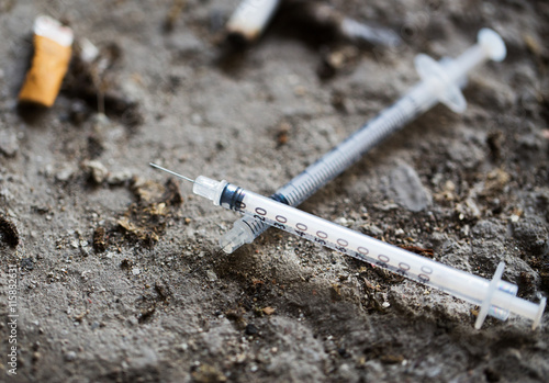 close up of syringe and smoked cigarette on ground photo