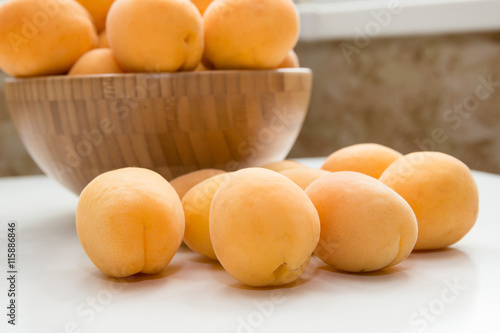 Apricot. Group of fresh fruits in a wooden bowl on a white table 
