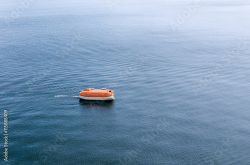 Lifeboat awaiting rescue in the wide expanse of the sea. Life boat is enclosed and rigid type rescue craft.