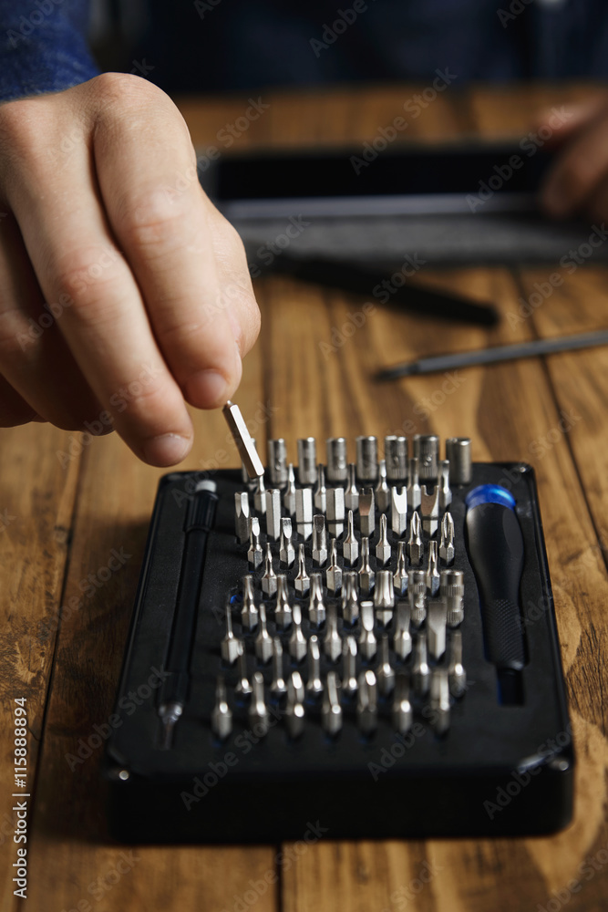 Hand takes small bit from toolkit driver set to use it with micro screwdriver Hand takes small bit from toolkit driver set to use it with micro screwdriver