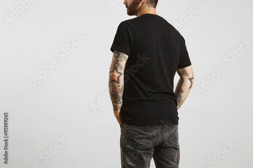 Fotografie Brutal attractive bearded biker man with tattooed hands poses backside in black