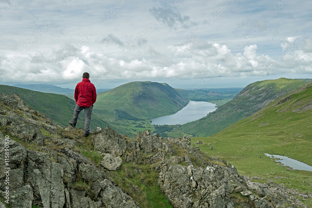 Man looks out over Wasdale Head from Beck Head on the slopes of Great Gable mountain in the the English Lake District National Park. Man looks out over Wasdale Head from Beck Head on the slopes of Great Gable mountain in the the English Lake District National Park.