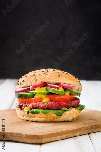 Veggie beet burger on a white wooden table and black background