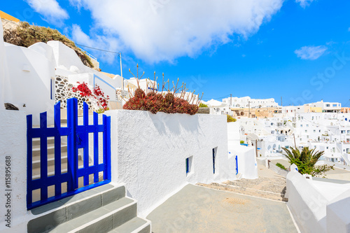 Blue gate on narrow street and typical Greek houses in Imerovigli village on Santorini island, Greece