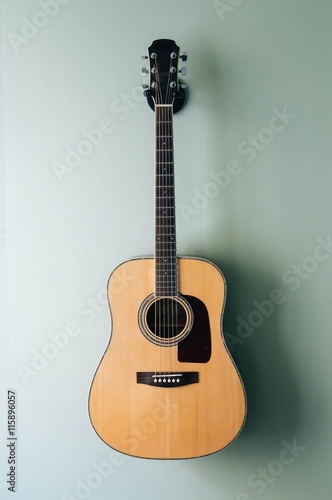 Acoustic guitar on guitar holder on the wall