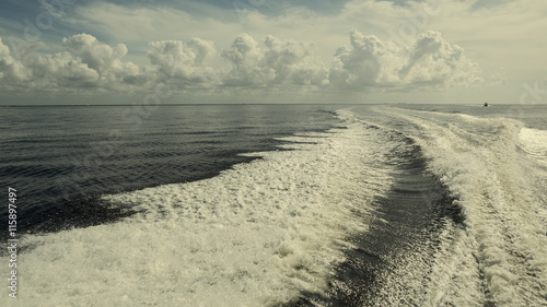 waves behind the boat on the sea with beautiful clouds. Nature c