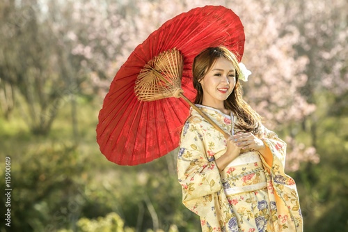 Asian woman with dress traditional Chameleon and red umbrella in