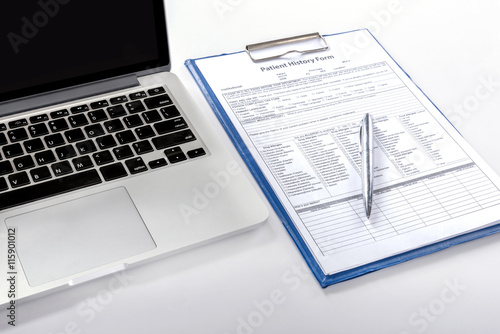 medical history from a patient with pen and computer notebook on doctor desk