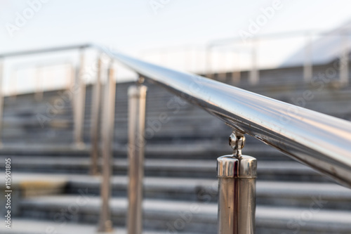 Public metal chrome handrail on gray staircase at city