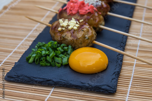 Tsukune - Japanese chicken yakitori meatballs served with chili sauce,  flakes, ground pepper and lemon wedges. photo