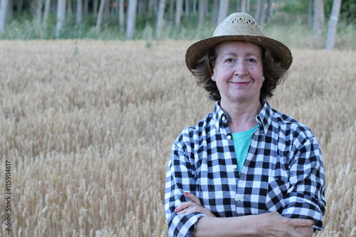 Canvas Print Portrait of mature female farmer smiling on farmland while crossing her arms