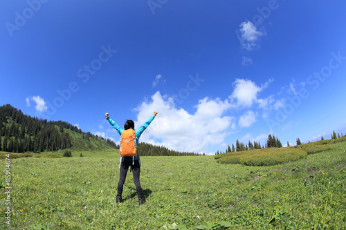 cheering young woman backpacker hiking on beautiful mountain peak