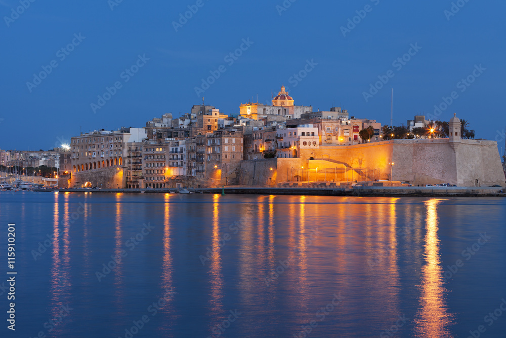 Fortified medieval walls of Malta reflecting in the Mediterranean sea at sunset 