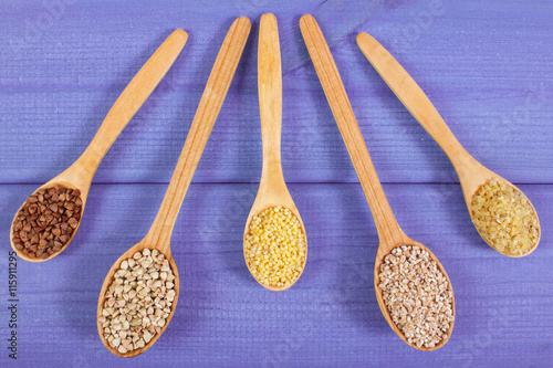 Various groats on wooden spoons, healthy food and nutrition