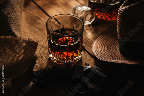 Glass of whiskey, revolver and hat