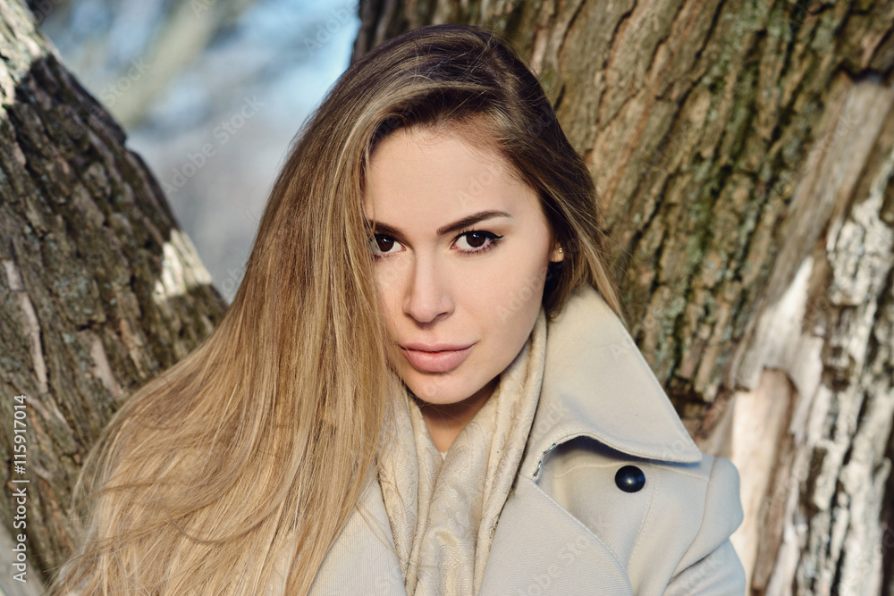 Fashionable portrait of lady with long hair in city. Image of brunette model on bright background. Young beautiful human in colorful coat in park. Adult female person wears street style outdoors Fashionable portrait of lady with long hair in city. Image of brunette model on bright background. Young beautiful human in colorful coat in park. Adult female person wears street style outdoors