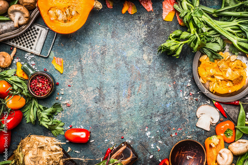 Autumn vegetables cooking preparation . Pumpkin, tomatoes, root vegetables and mushrooms ingredients on dark rustic background for  Thanksgiving Day recipes or menu card, top view, frame photo