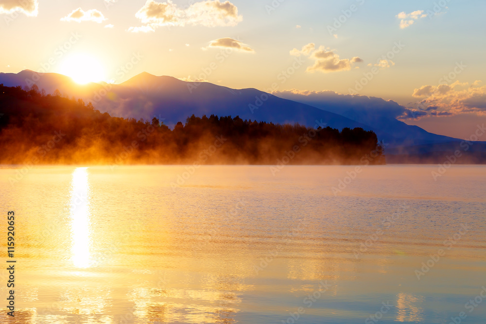 Naklejka premium beautiful landscape with mountains and lake at dawn in golden, blue and purple tones.