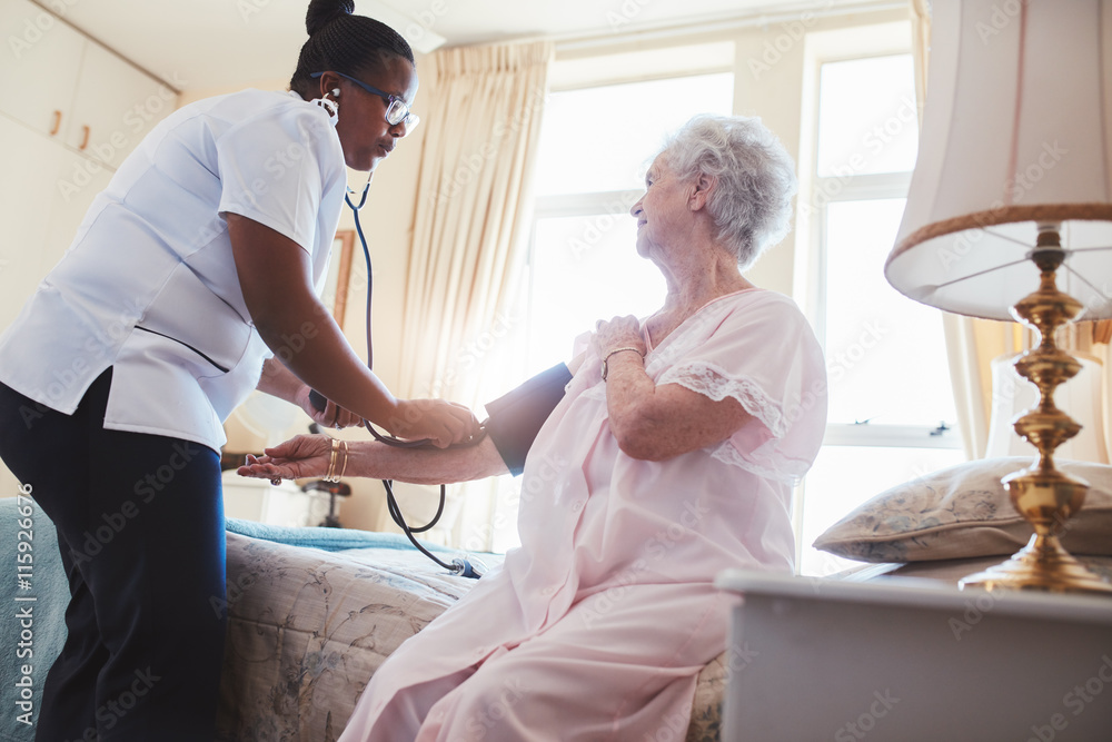Obraz premium Female nurse checking blood pressure of a senior woman