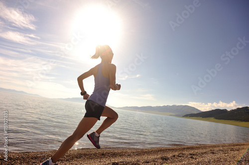 healthy lifestyle young woman runner running on sunrise seaside road